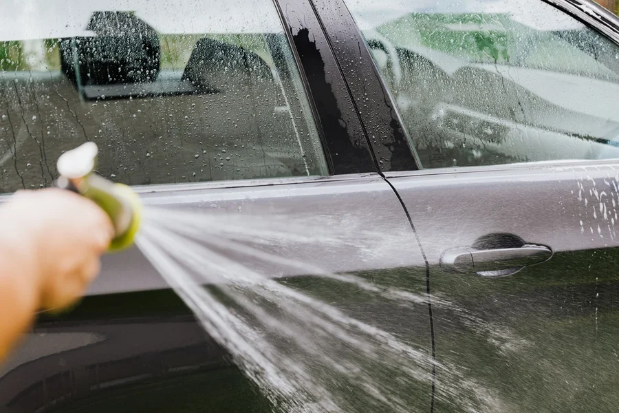 soapy car mats wash Rinsing a rubber car mat with a garden hose outdoors