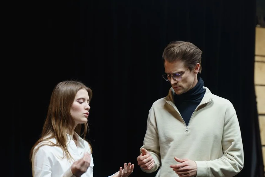 Actors performing on a brightly lit theater stage
