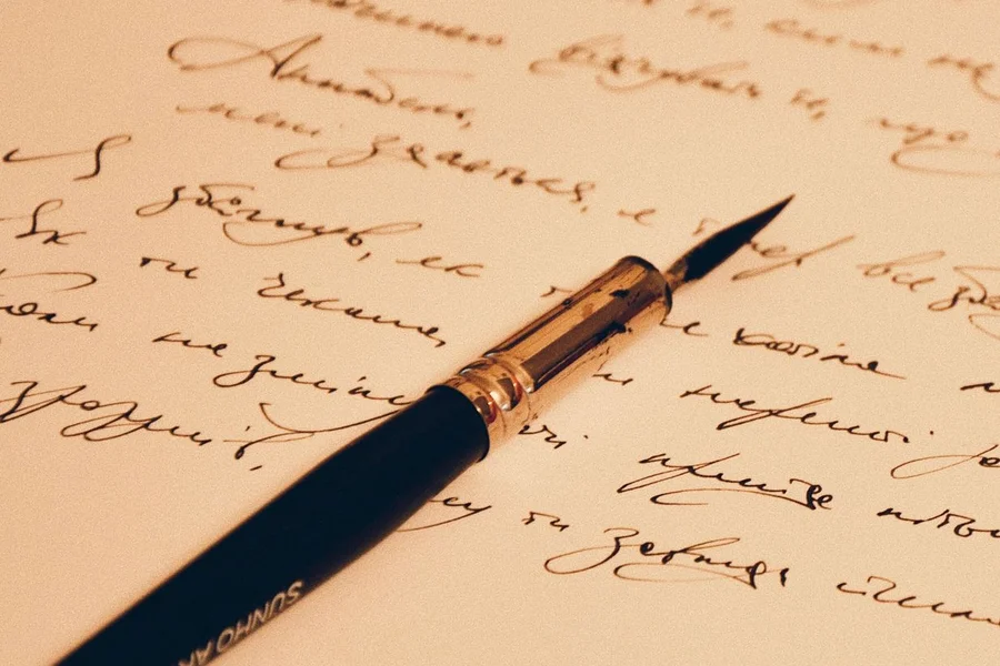Vintage fountain pen and ink well on parchment paper