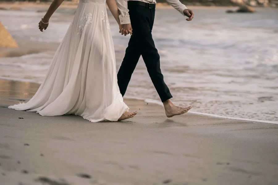 destination wedding couple Wedding couple walking on a sunny beach coastline
