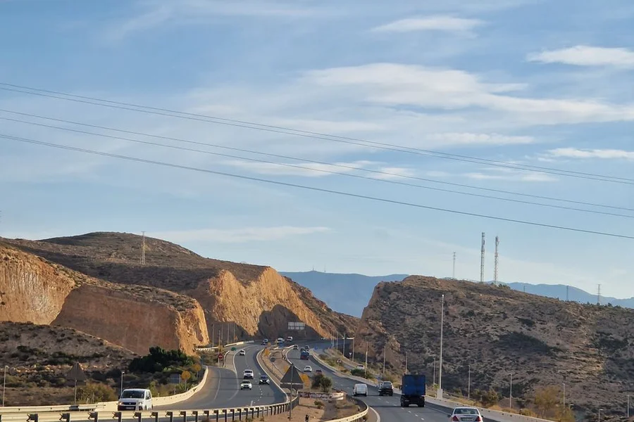Highway stretching through scenic desert mountains under a clear blue sky
