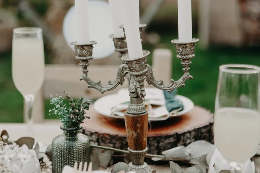 A dinner table set with wine glasses and plates under warm lights