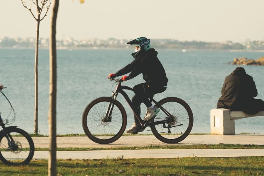 Cyclist riding along a scenic lake shore path surrounded by trees
