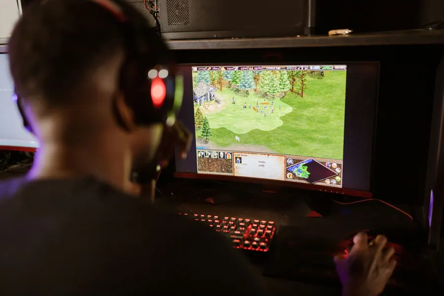 Gamer playing an open world RPG on a desktop computer with glowing keyboard